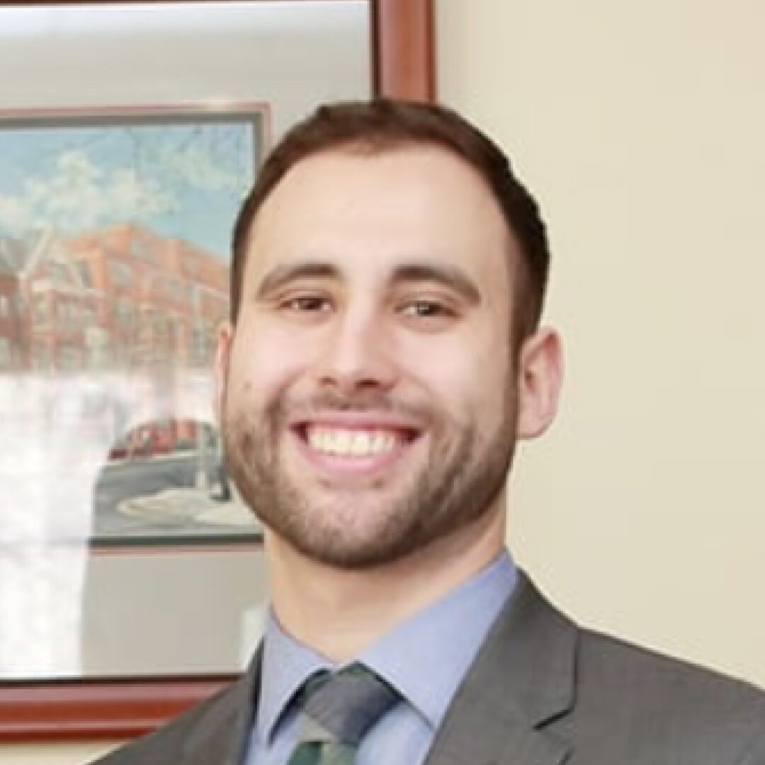 Smiling man in a suit with background art.